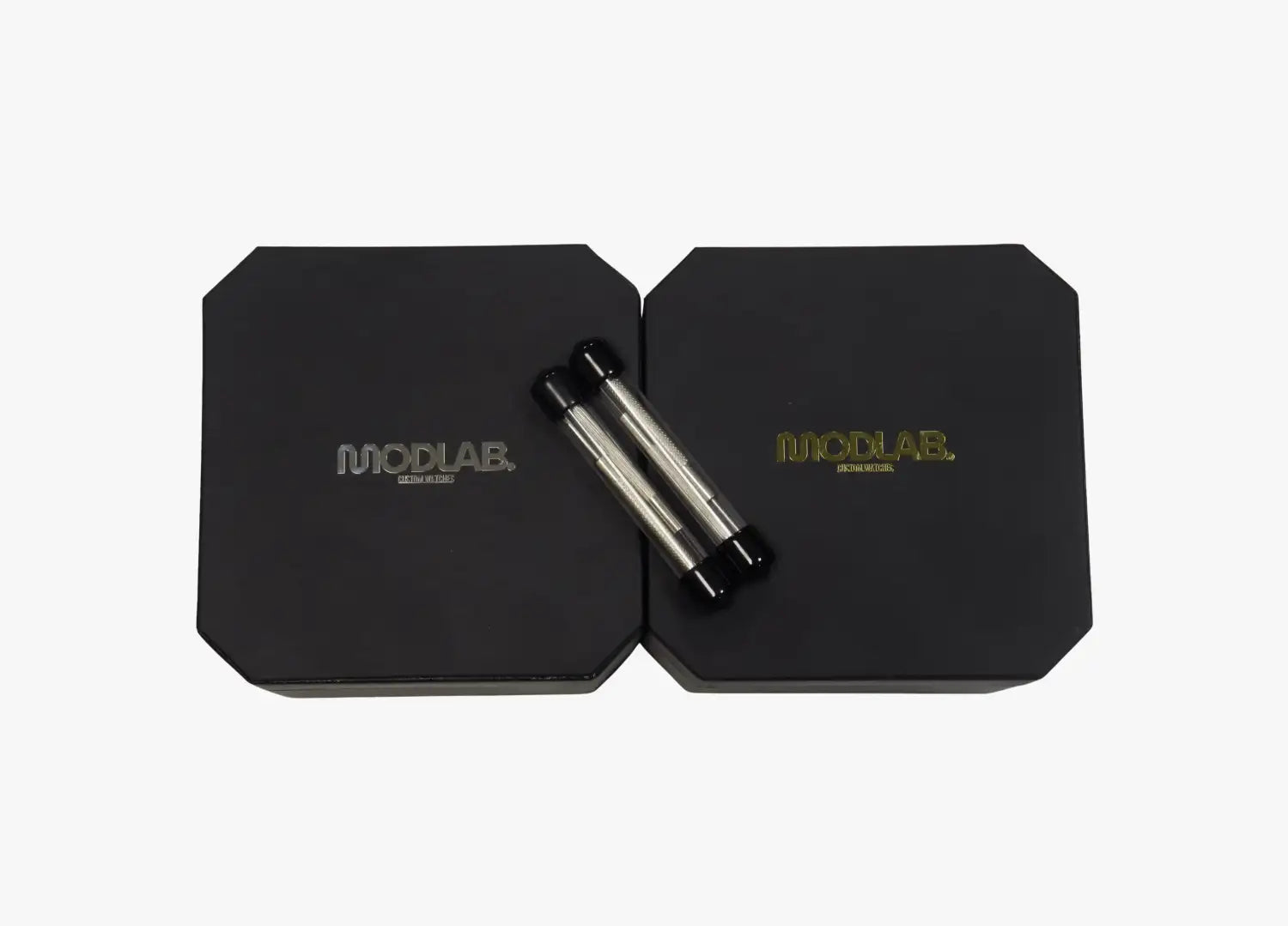 Black modlab branded boxes with silver and black cylindrical objects resting on top.