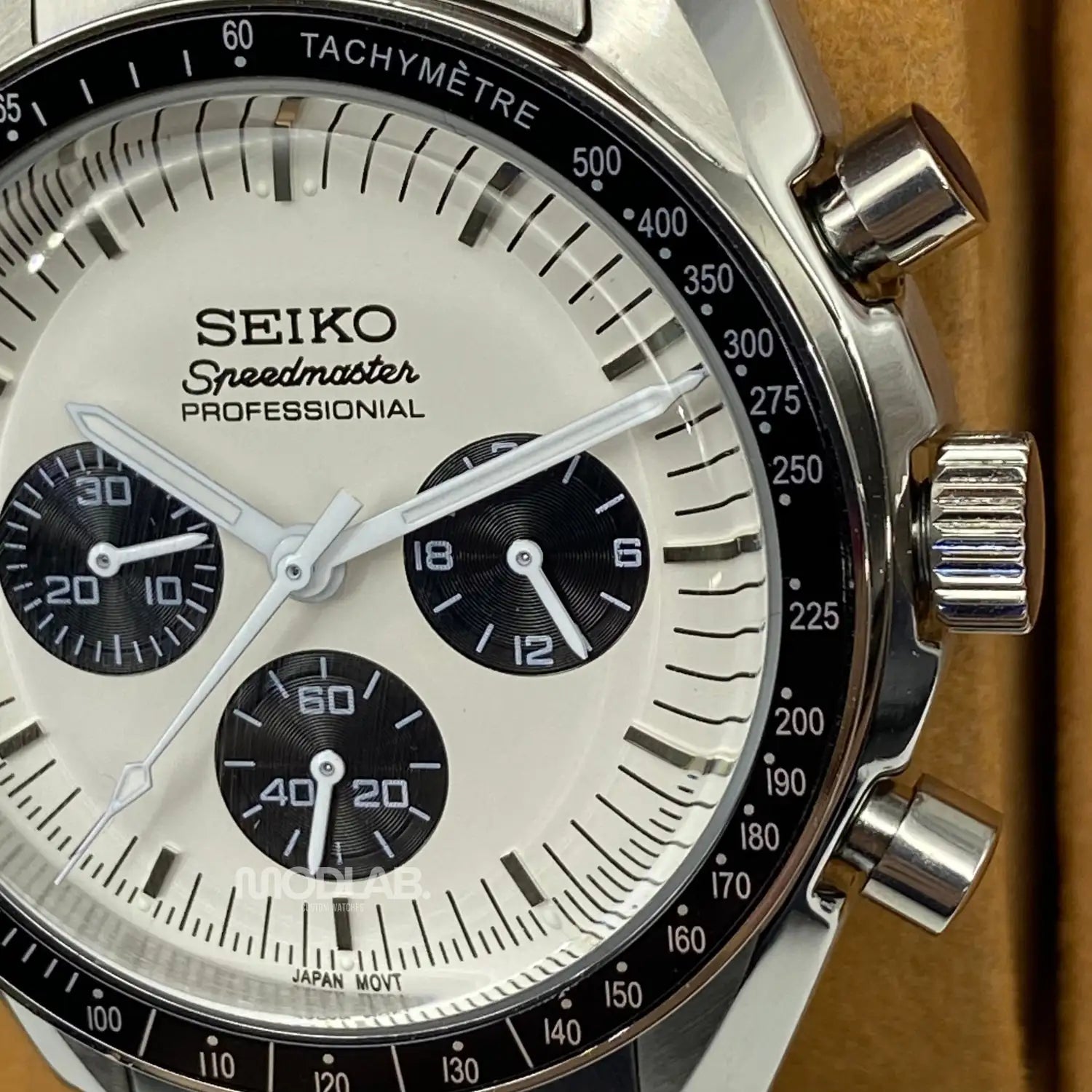 A sleek silver seiko speedmaster professional chronograph watch with a white dial, black subdials and tachymeter bezel.