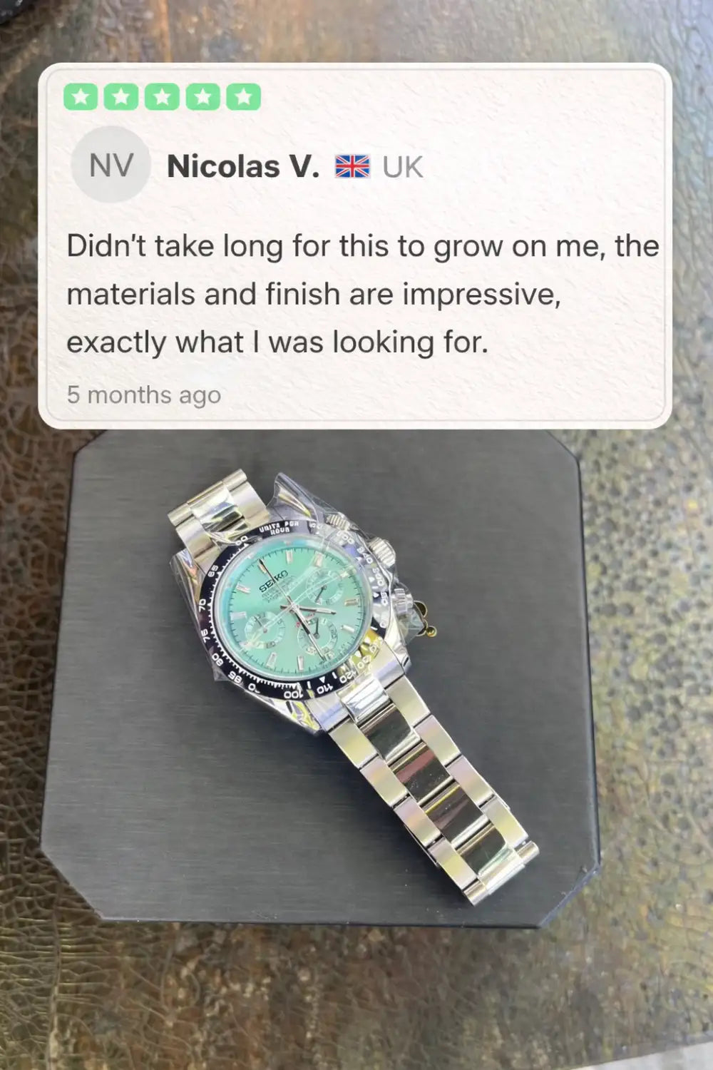 A sleek silver stainless steel seiko chronograph watch with a vibrant turquoise dial and black bezel.